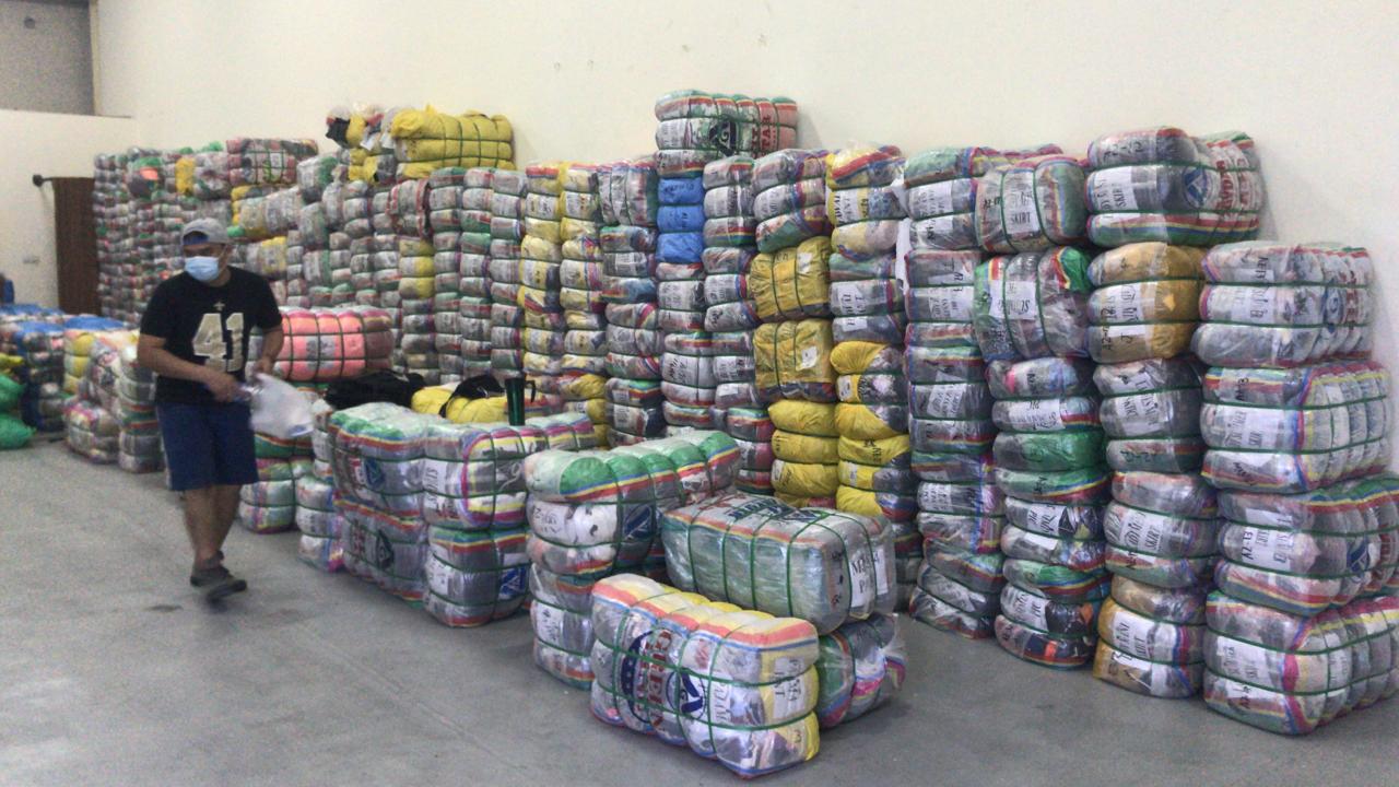 Floor-to-ceiling wall of graded wholesale used clothing bales inside the Manila Fashion Dubai warehouse