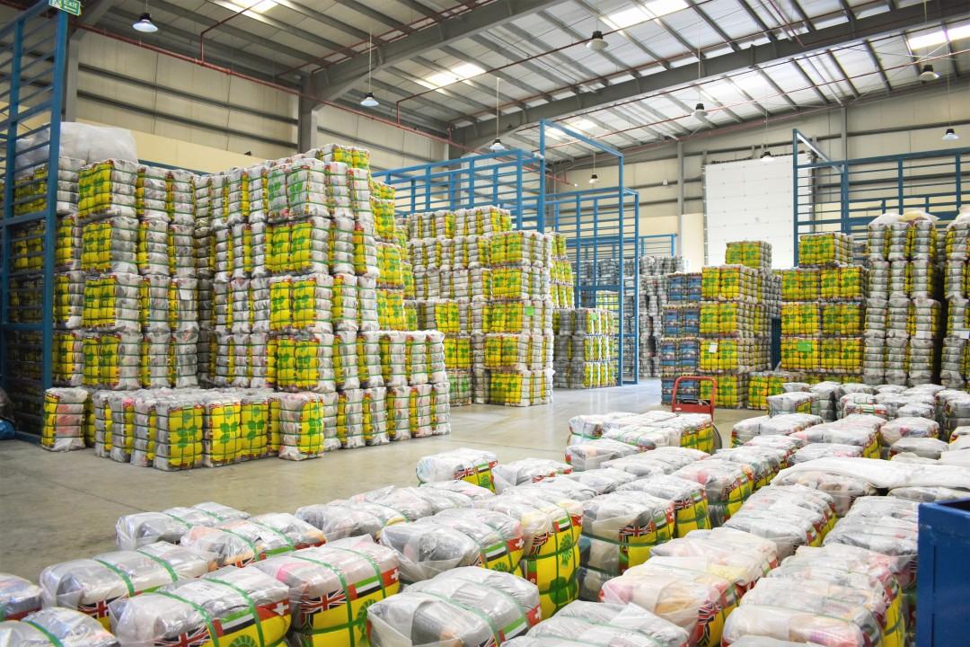 Massive Dubai warehouse hall stacked with yellow-wrapped wholesale used clothing bales ready for export